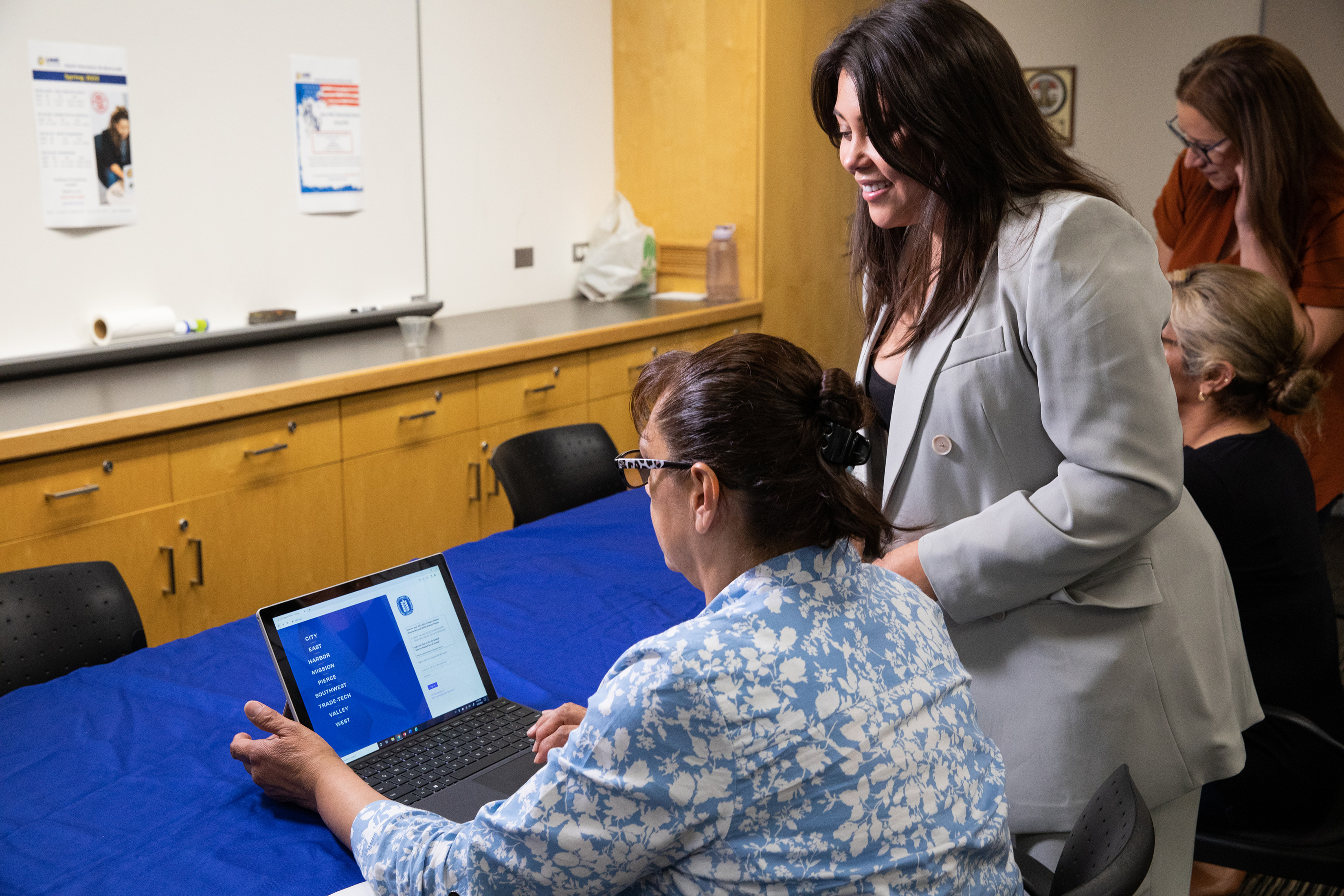 Teacher Guiding a Person Using a Laptop