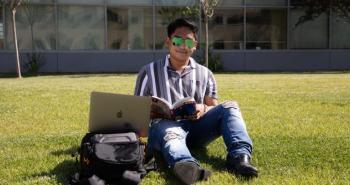 student sitting on lawn on campus