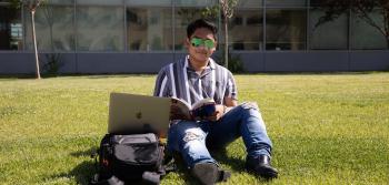 Student Sitting in the Grass with Sunglasses