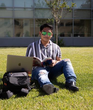 Student Sitting in the Grass with Sunglasses