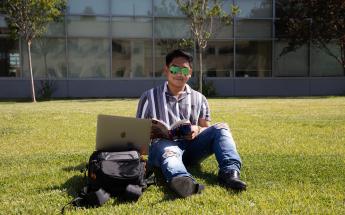 Student Sitting in the Grass with Sunglasses