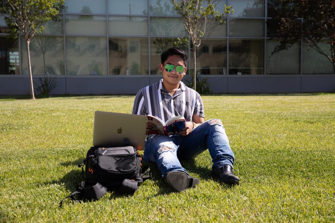 Student Sitting in the Grass with Sunglasses